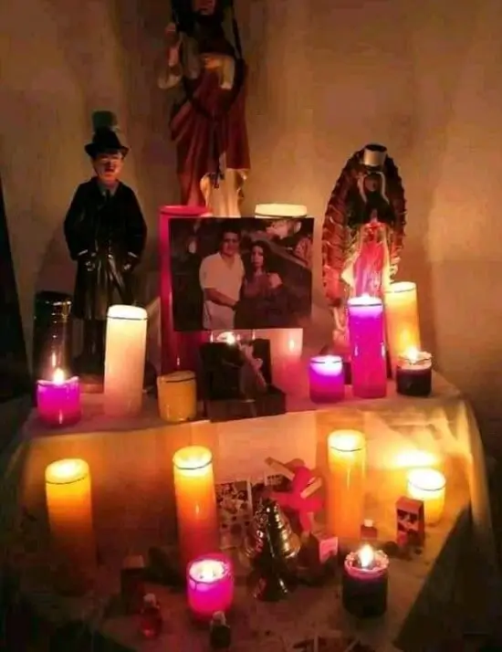 Altar con imágenes de santos, flores y velas encendidas